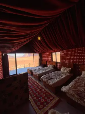 a room with four beds and a curtain and a window at Wadi Rum Nights Tents in Wadi Rum