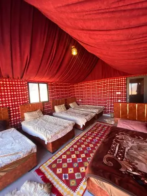 a room with four beds and a red curtain at Wadi Rum Nights Tents in Wadi Rum