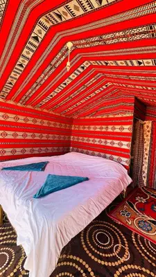 a bed in a room with a red wall at Desert Nights camp in Aqaba