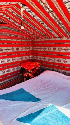 a bed in a room with a red and white ceiling at Desert Nights camp in Aqaba