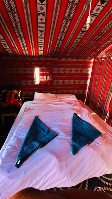 a bed with two blue pillows on top of it at Desert Nights camp in Aqaba