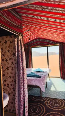 a bed in the middle of a room with a window at Desert Nights camp in Wadi Rum