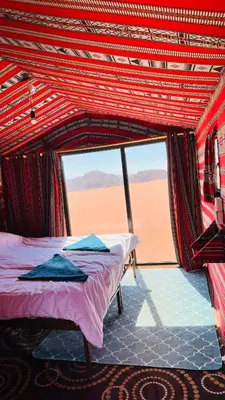 a bed in a room with a view of the desert at Desert Nights camp in Wadi Rum