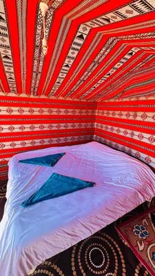 a bed in a room with a red ceiling at Desert Nights camp in Wadi Rum