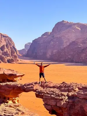 a man standing on a rock in the desert at ELENA lUXURY CAMP in Wadi Rum