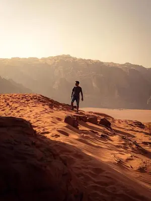 a man standing on a rock in the desert at ELENA lUXURY CAMP in Wadi Rum