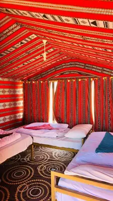a group of beds in a room with red walls at Desert Nights camp in Aqaba
