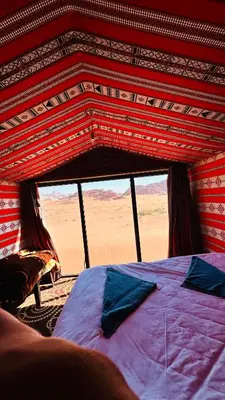 a bed in a room with a view of the desert at Desert Nights camp in Wadi Rum