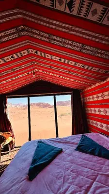 a bed in a room with a view of the desert at Desert Nights camp in Wadi Rum
