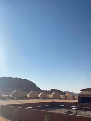 a row of tents in the desert with mountains in the background at عماد رم in Wadi Rum