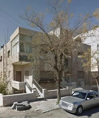 a car parked in a parking lot in front of a building at small house in Amman