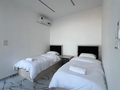 two beds in a room with white walls at Bellagio Chaleht in Al Rama