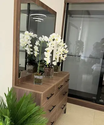 a dresser with vases with white flowers on it at شقة lvaisa الفندقيه in Umm Uthainah