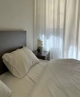 a white bed with a pillow next to a window at شقة lvaisa الفندقيه in Umm Uthainah
