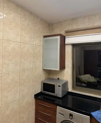 a kitchen with a microwave on a counter and a window at شقة lvaisa الفندقيه in Umm Uthainah