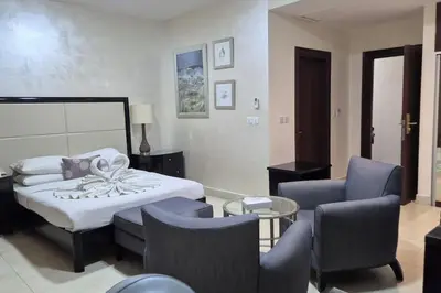 a bedroom with a bed and chairs and a table at Le Shot tours Hotel in Al Jafr