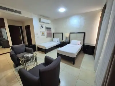 a hotel room with two beds and a couch and chairs at Le Shot tours Hotel in Al Jafr