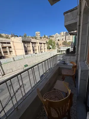 a balcony with two chairs and a table and a view at Cozy Studio in a Creative Hub in Amman