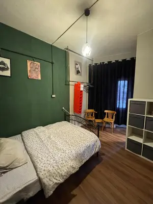 a bedroom with a bed and a green wall at Cozy Studio in a Creative Hub in Amman