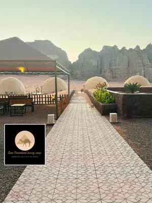 a walkway leading to a beach with a tent at Rum Dreamland luxury camp in Wadi Rum
