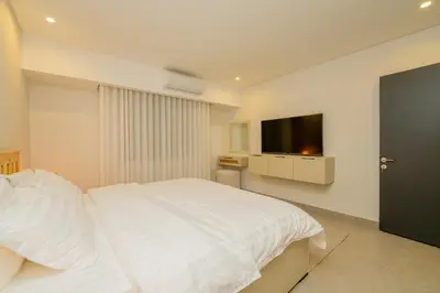 a bedroom with a white bed and a flat screen tv at Maria Suites 2 in Aqaba