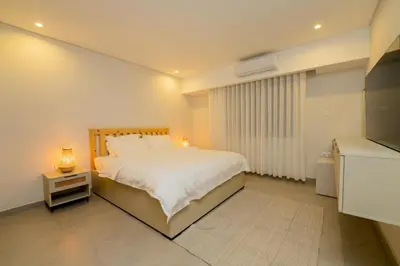 a bedroom with a white bed and a television at Maria Suites 1 in Aqaba