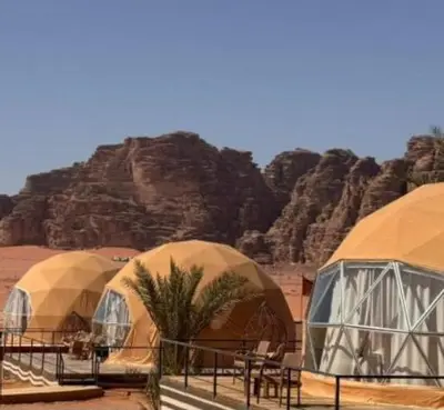 a row of domes in a desert with mountains at Wadi Rum, the best stars in Wadi Rum