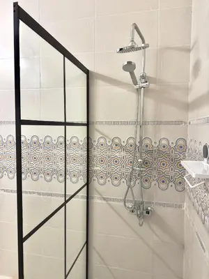 a shower with a glass door in a bathroom at Turath by Badiya 2BR Apt In Luweibdeh in Amman