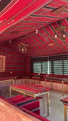 a dining room with red walls and tables and chairs at Desert Time in Wadi Rum