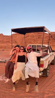 a group of people sitting on the back of a truck in the desert at Desert Time in Wadi Rum
