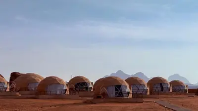 a row of tents in the desert with mountains in the background at HAGIA SOPHIA lUXURY CAMP in Disah