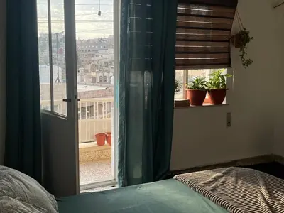 a bedroom with a window with a view of a city at Central apartment with beautiful view in Amman
