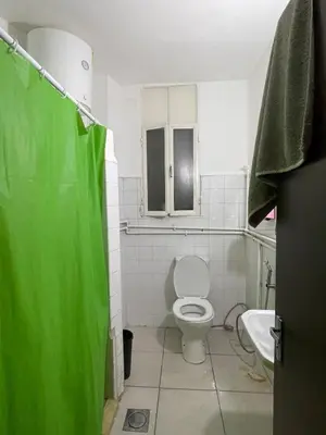 a white bathroom with a toilet and a sink at Central apartment with beautiful view in Amman