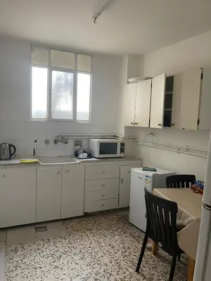 a white kitchen with a sink and a microwave at Central apartment with beautiful view in Amman