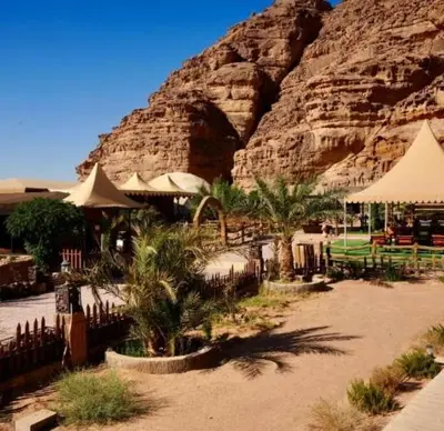 a resort with tables and umbrellas in front of a mountain at Wadi Rum Salem in Wadi Rum