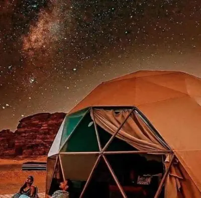 a woman is standing next to a tent under the stars at Wadi Rum Salem in Wadi Rum