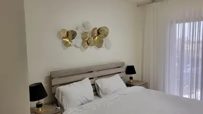 a bedroom with a bed with white sheets and butterflies on the wall at Lavender Résidence in Amman