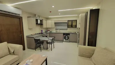 a kitchen and living room with a couch and a table at Lavender Résidence in Amman