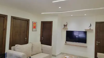 a living room with a couch and a tv on a wall at Lavender Résidence in Amman