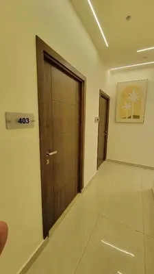 a hallway with a wooden door and a tile floor at Lavender Résidence in Amman