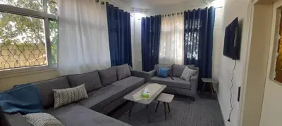 a living room with a gray couch and blue curtains at Two Palms Housing in Jerash