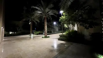 a courtyard with palm trees and lights at night at Luxury Suite in Aqaba AlRaha Village Marsa Zayed in Aqaba