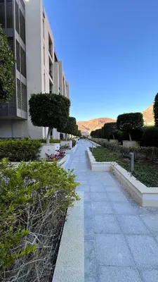 a walkway next to a building with bushes and trees at Luxury Suite in Aqaba AlRaha Village Marsa Zayed in Aqaba