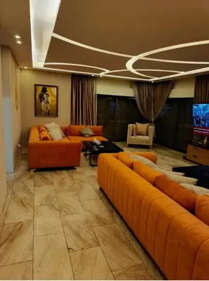 a living room with orange couches and a flat screen tv at روف طابق ثاني تشطيب فندقي باطلاله ساحرة بعمارة عائلات بعبدون الشمالي in Amman