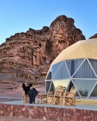 a woman sitting in a chair in front of a tent at Wadi Rum Karolina Bubbles camp in Wadi Rum