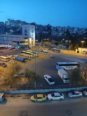 a parking lot with parked cars and buses at Kahraman Amman Hotel in Amman