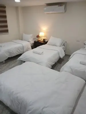 a room with three beds with white sheets at Kahraman Amman Hotel in Amman
