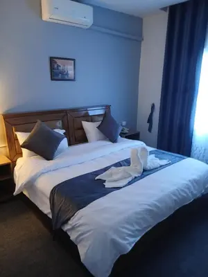 two beds in a hotel room with a robe on them at Kahraman Amman Hotel in Amman