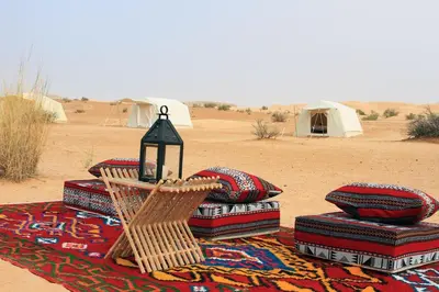 a blanket with pillows and tents in the desert at 1moon valley camp in Al Jafr