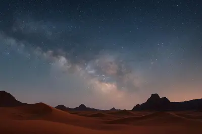 a desert under a starry sky with mountains in the background at 1moon valley camp in Al Jafr